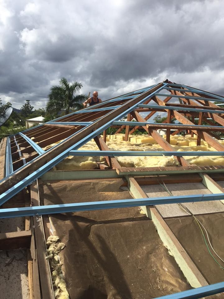 A Man is Working on the Roof of a House — Bradshaw Plumbing & Roofing Pty Ltd In East Mackay, QLD
