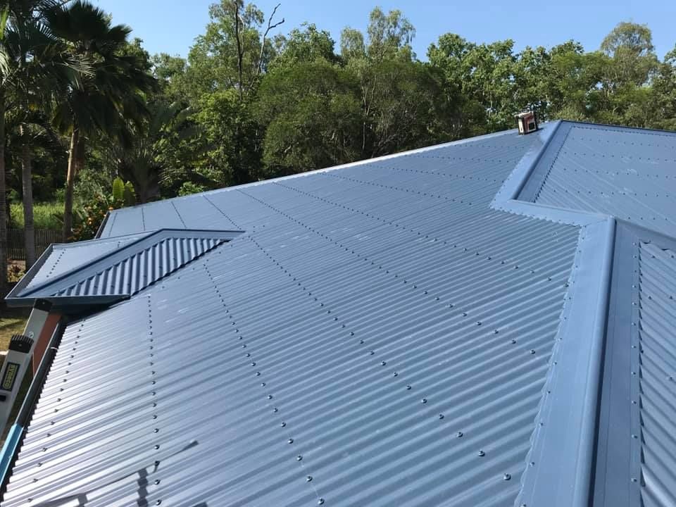 A Blue Corrugated Metal Roof on a House With Tree — Bradshaw Plumbing & Roofing Pty Ltd In East Mackay, QLD