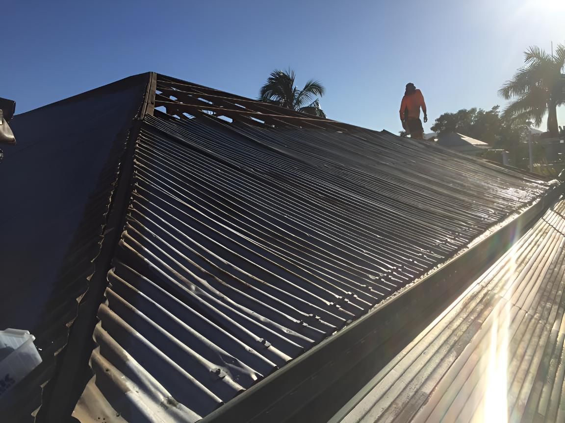 A Man is Standing on the Roof of a Building — Bradshaw Plumbing & Roofing Pty Ltd In East Mackay, QLD