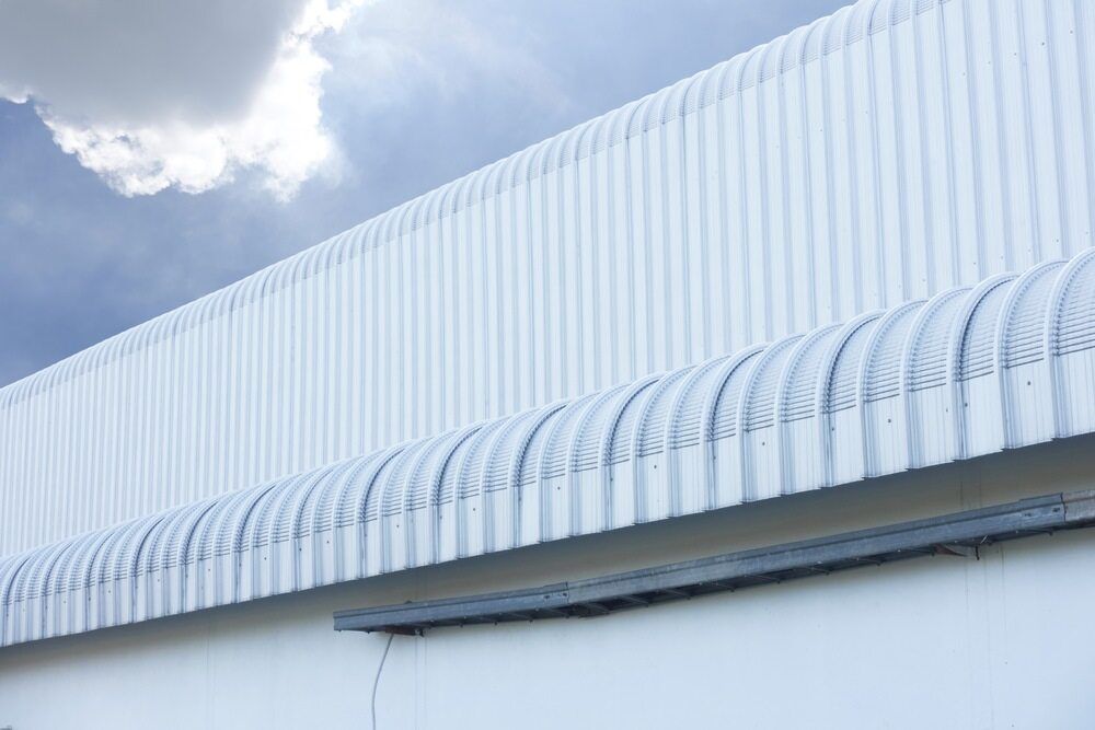 A White Building With a Curved Roof and a Blue Sky in the Background — Bradshaw Plumbing & Roofing Pty Ltd In Paget, QLD A White Building With a Curved Roof and a Blue Sky in the Background — Bradshaw Plumbing & Roofing Pty Ltd In Paget, QLD