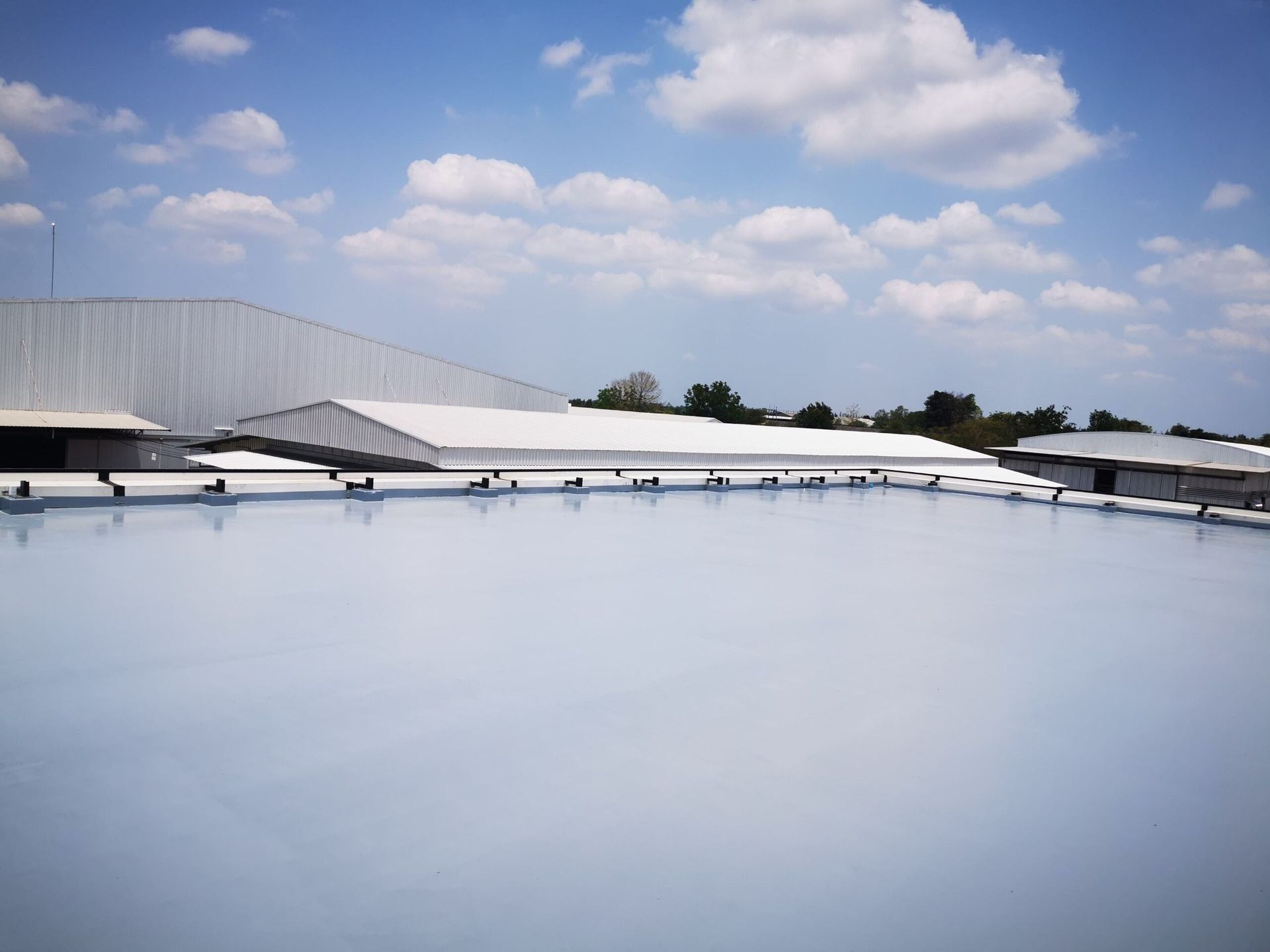 A Large White Building With a Blue Sky in the Background — Bradshaw Plumbing & Roofing Pty Ltd In Marian, QLD A Large White Building With a Blue Sky in the Background — Bradshaw Plumbing & Roofing Pty Ltd In Marian, QLD