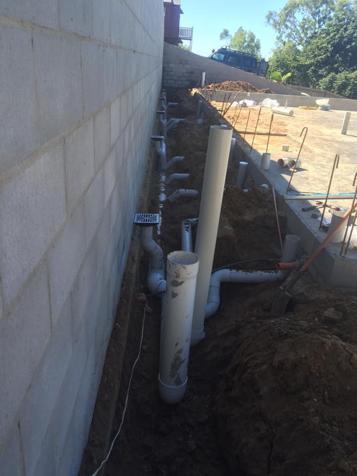 A Bunch of Pipes Are Being Installed on the Side of a Building — Bradshaw Plumbing & Roofing Pty Ltd In East Mackay, QLD