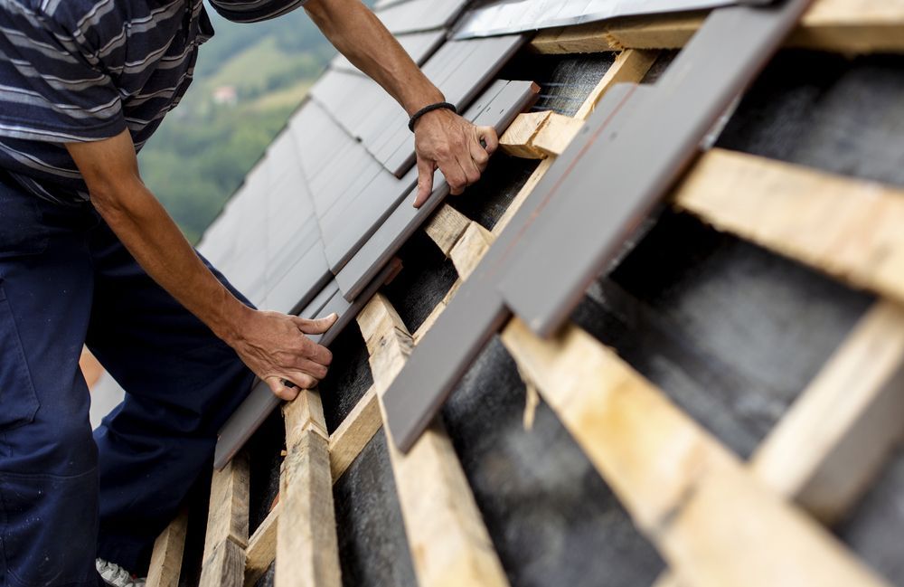A Man is Working on the Roof of a House — Bradshaw Plumbing & Roofing Pty Ltd In Ooralea, QLD A Man is Working on the Roof of a House — Bradshaw Plumbing & Roofing Pty Ltd In Ooralea, QLD