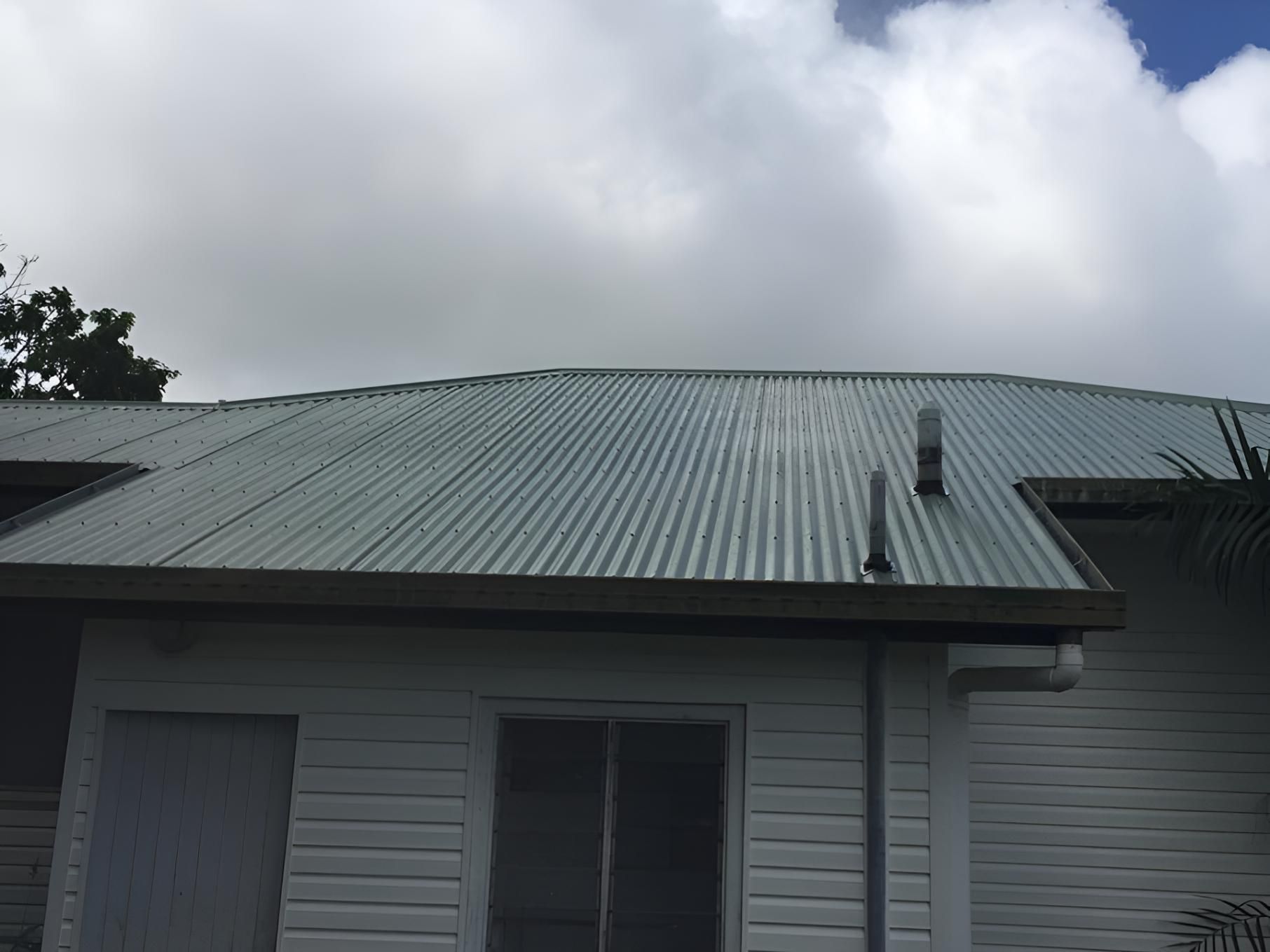 A White House With a Metal Roof and a Window — Bradshaw Plumbing & Roofing Pty Ltd In East Mackay, QLD