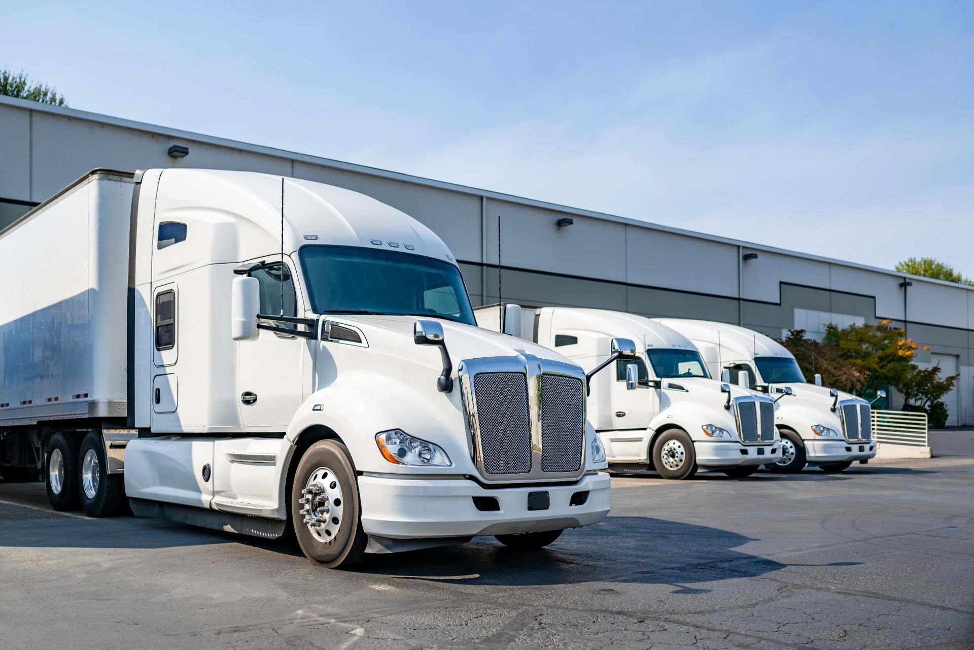 A row of white semi trucks parked in front of a building.