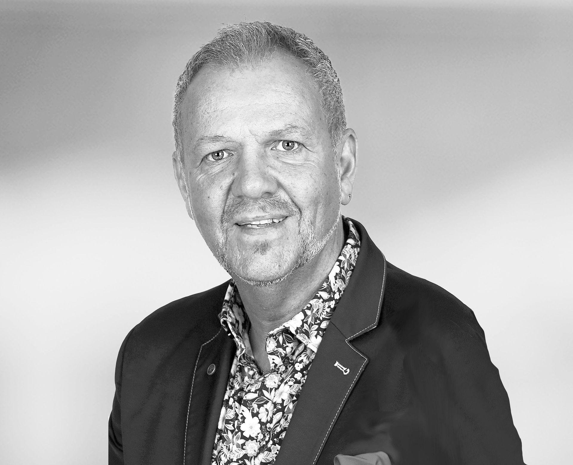 Auf einem Schwarzweißfoto lächelt ein Mann mit Bart.