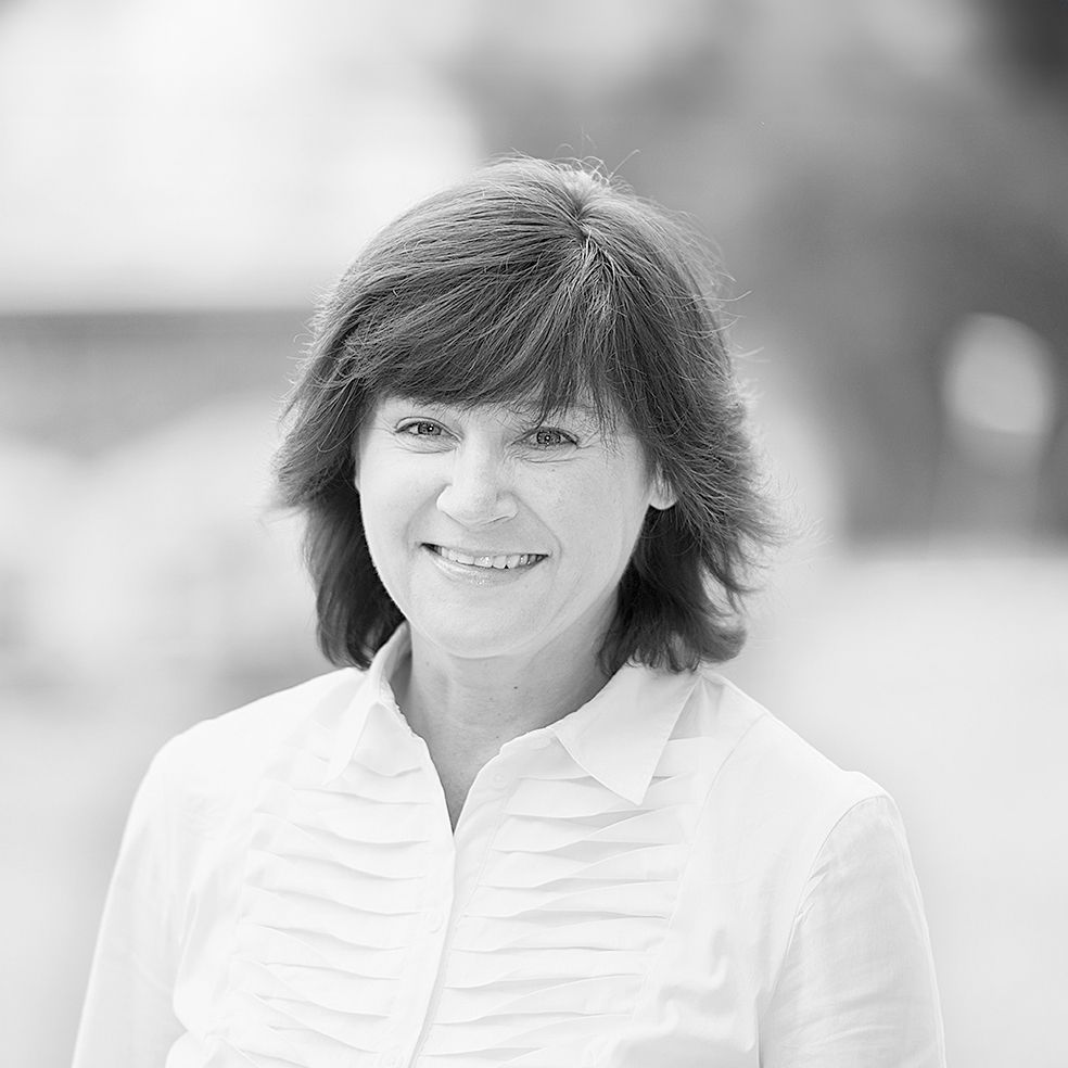 Auf einem Schwarzweißfoto lächelt eine Frau in einem weißen Hemd.