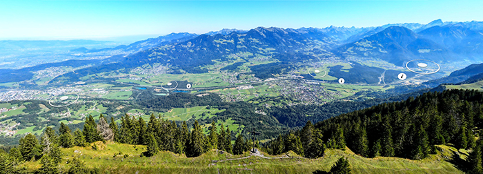 Ein Blick auf ein Tal mit Bergen im Hintergrund und einer Stadt in der Ferne.