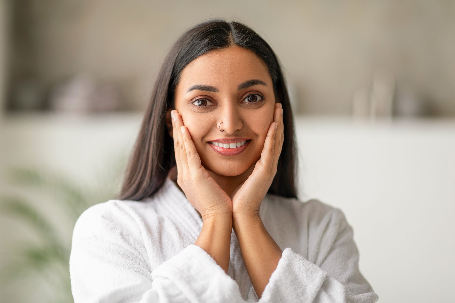 a woman in a bathrobe is smiling and touching her face .