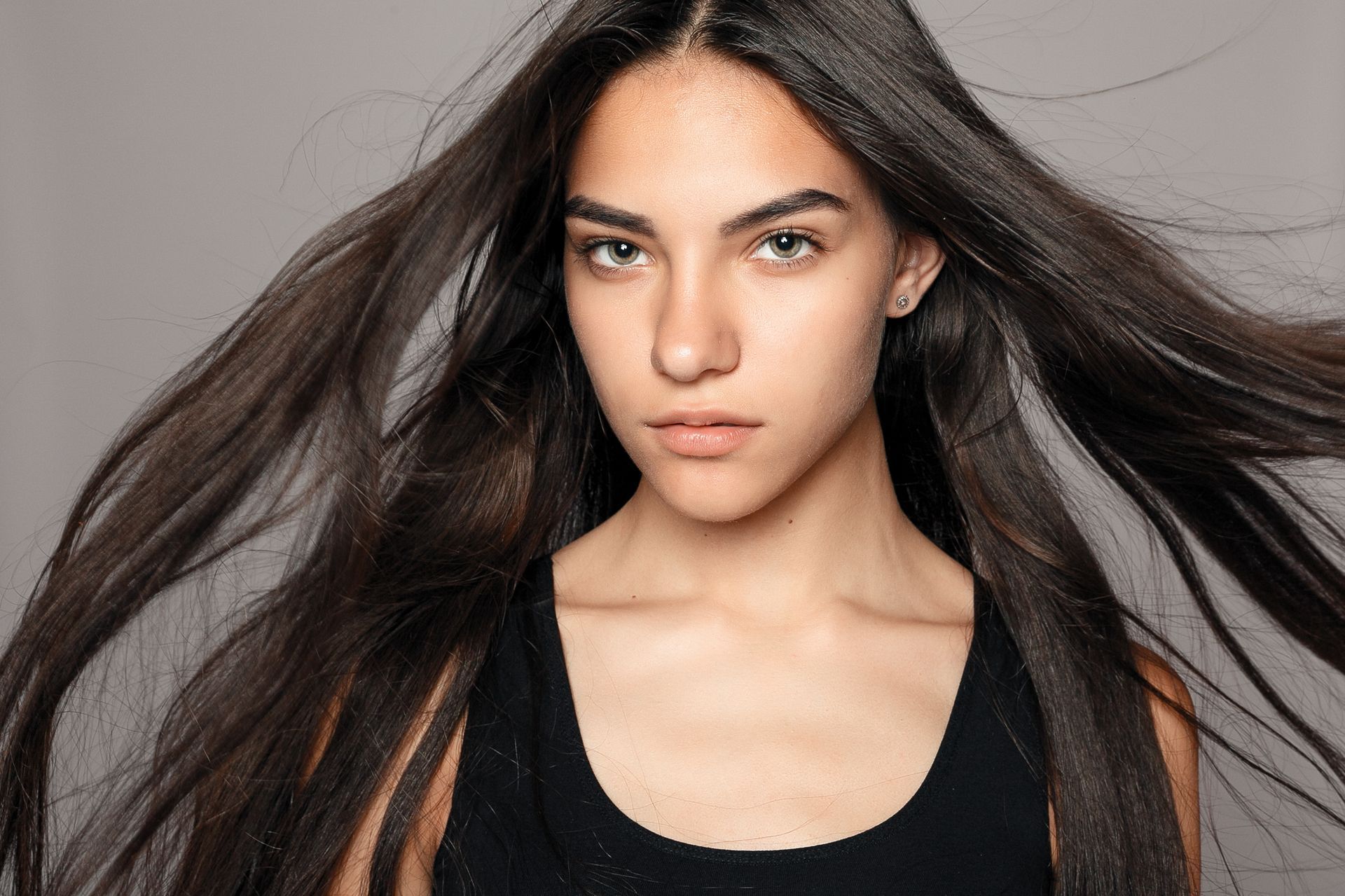 A woman with long hair is wearing a black tank top.