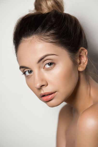 a woman with her hair in a bun is looking at the camera .