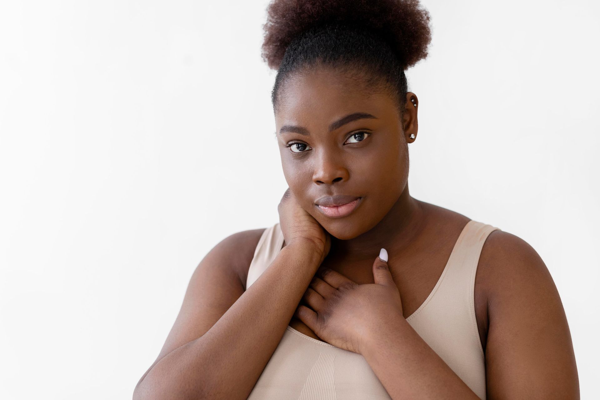 A woman is holding her hand to her chest and looking at the camera.