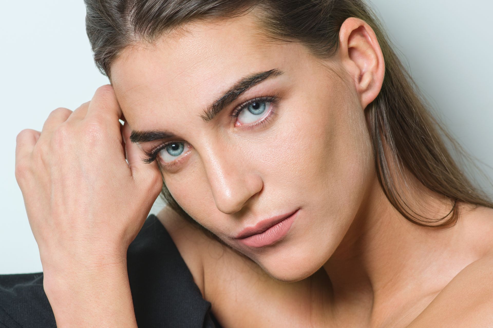 a close up of a woman 's face with her hand on her face .