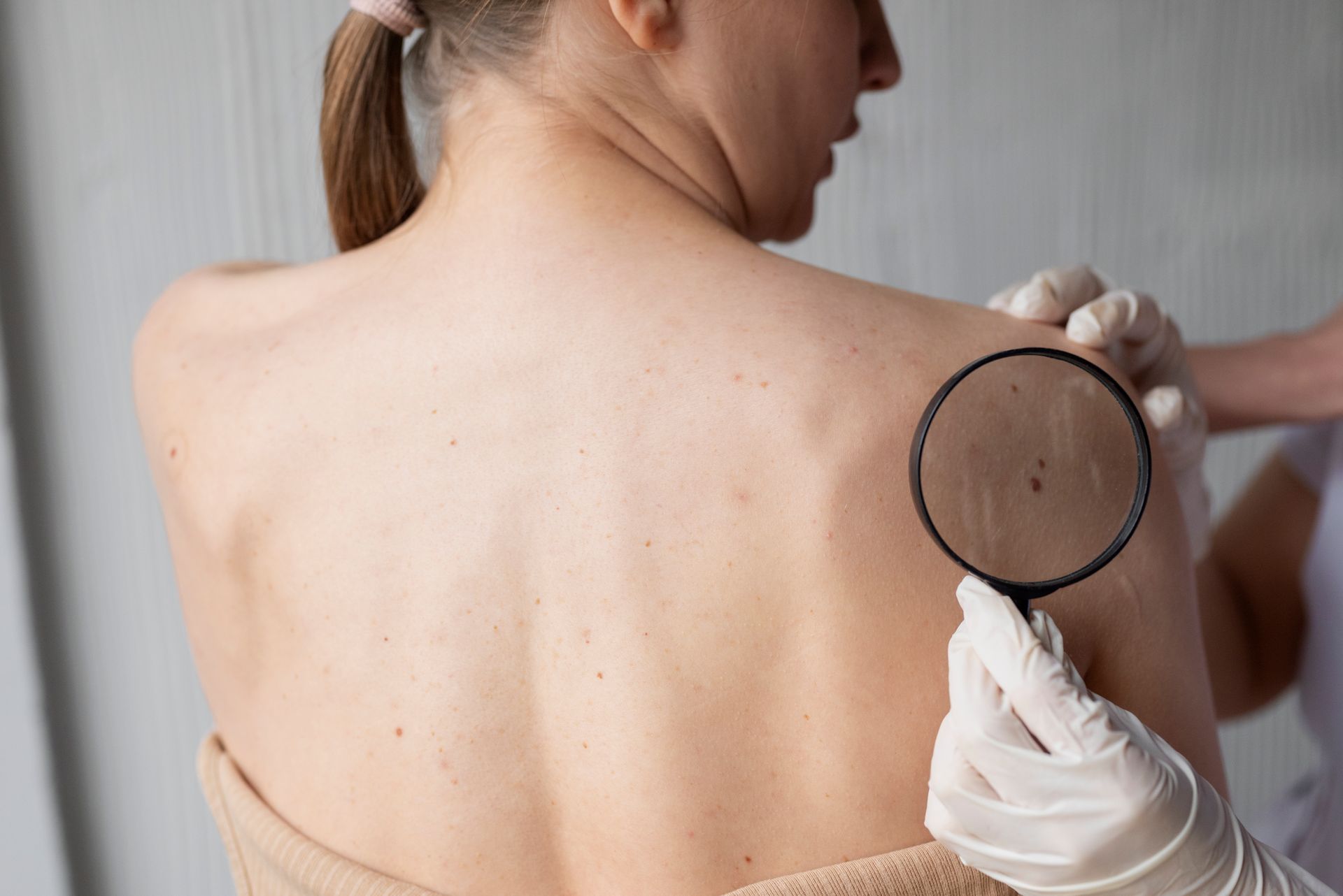 A doctor is examining a woman 's back with a magnifying glass.