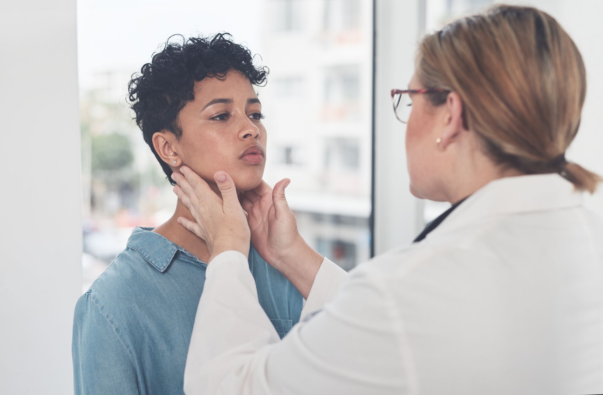 Doctor examining a patient's neck in a medical office.