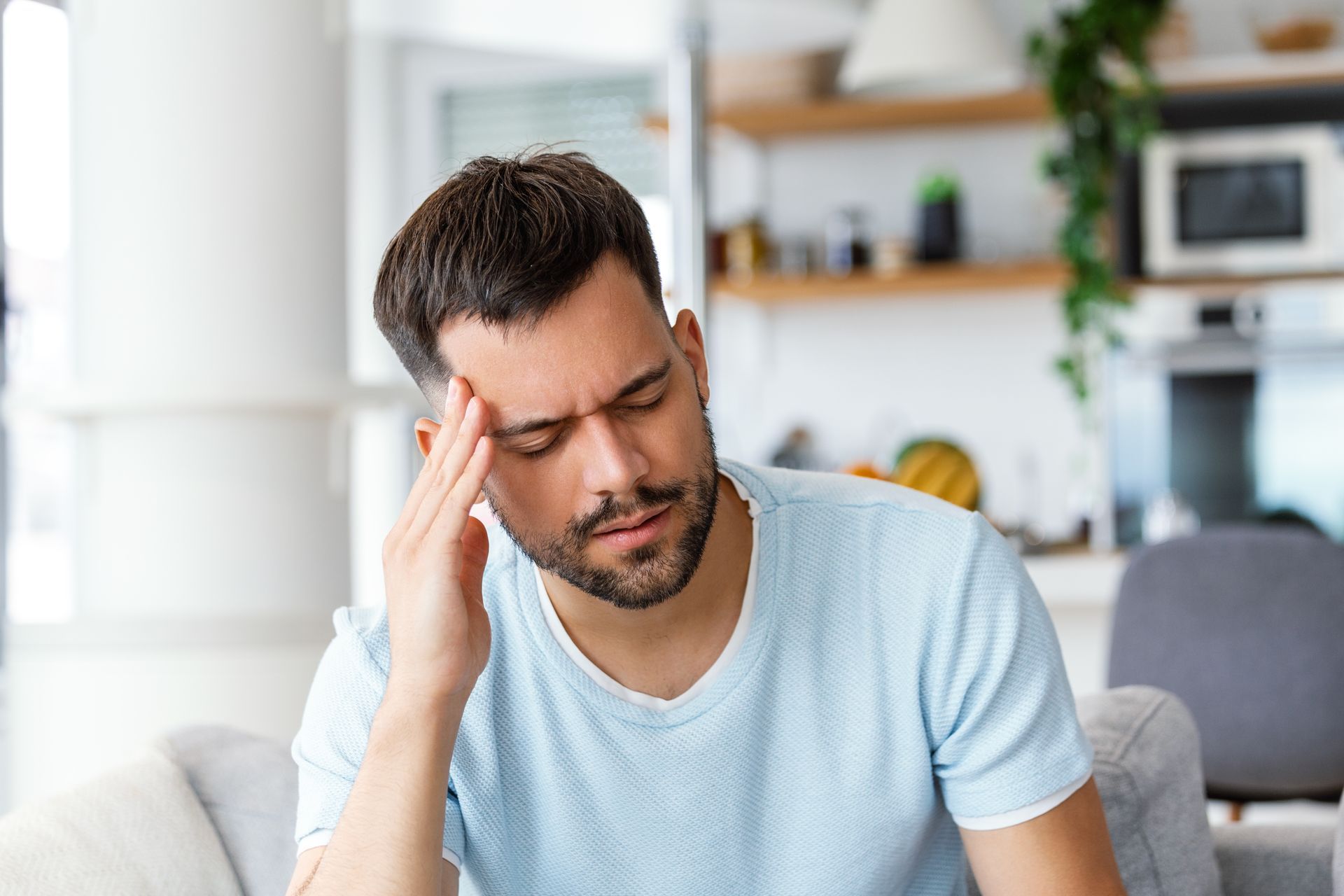 a man is sitting on a couch with a headache .