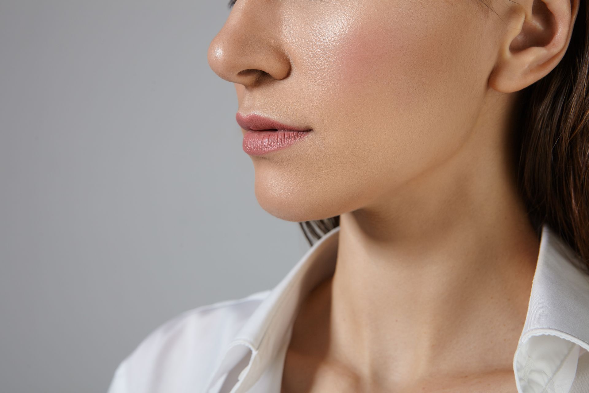 a close up of a woman 's neck and face on a gray background .