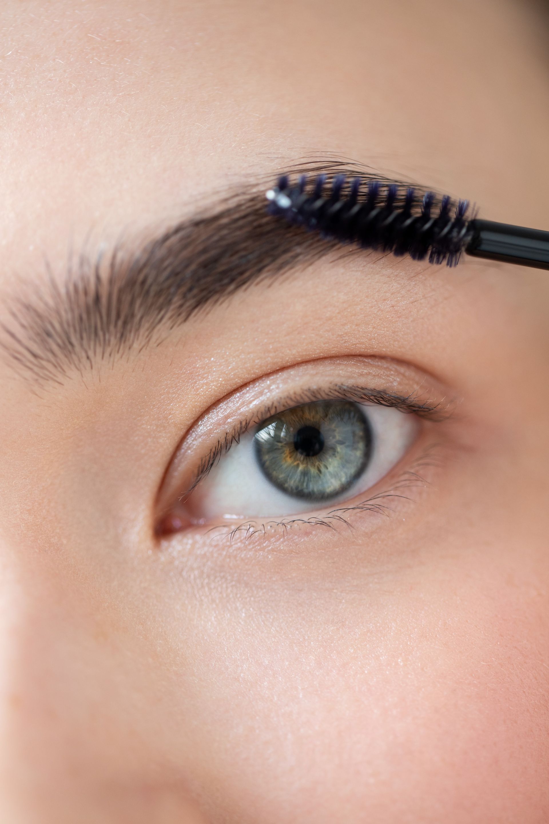 a woman is applying mascara to her eyebrows with a brush .