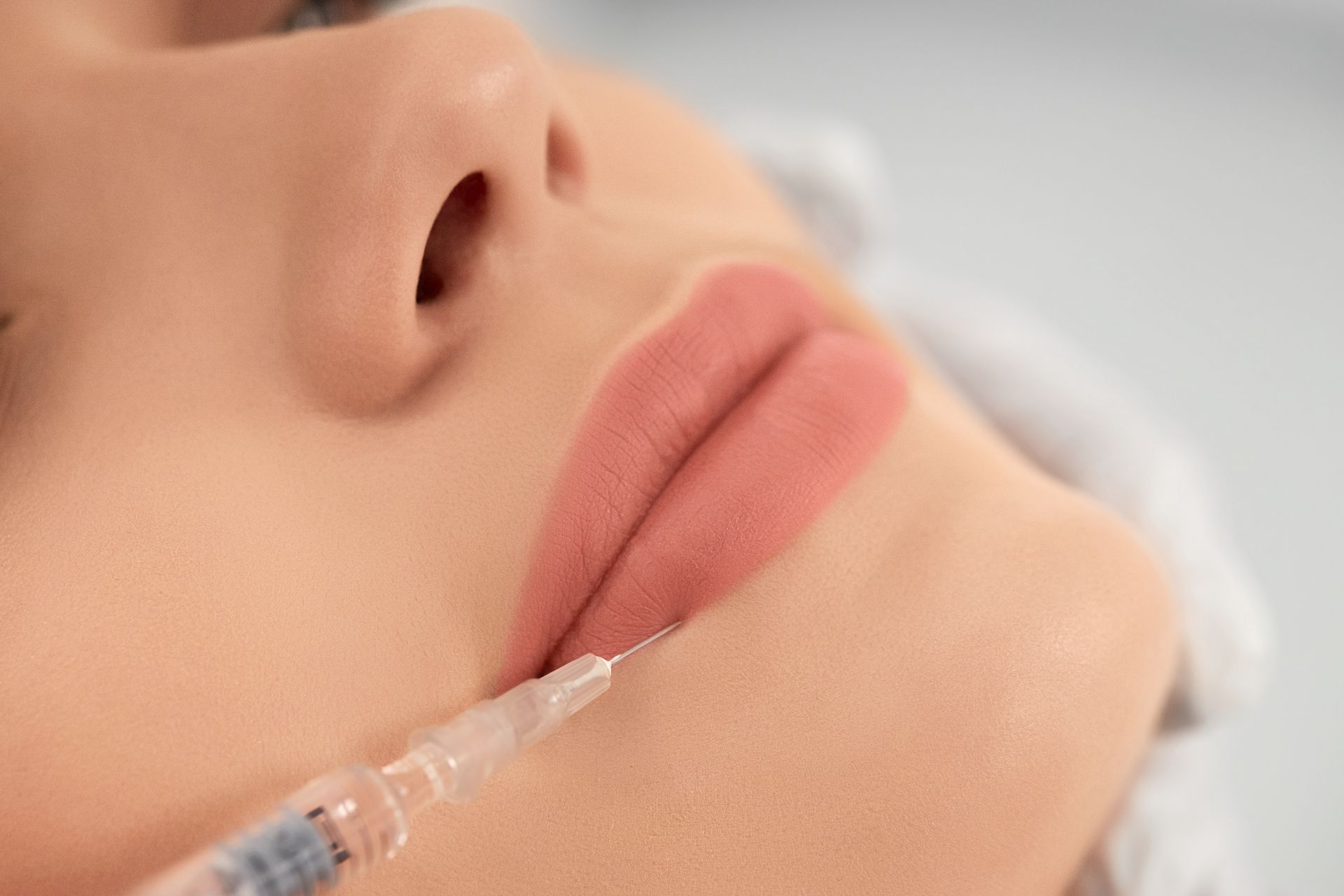 Lips being injected with filler during a cosmetic procedure.
