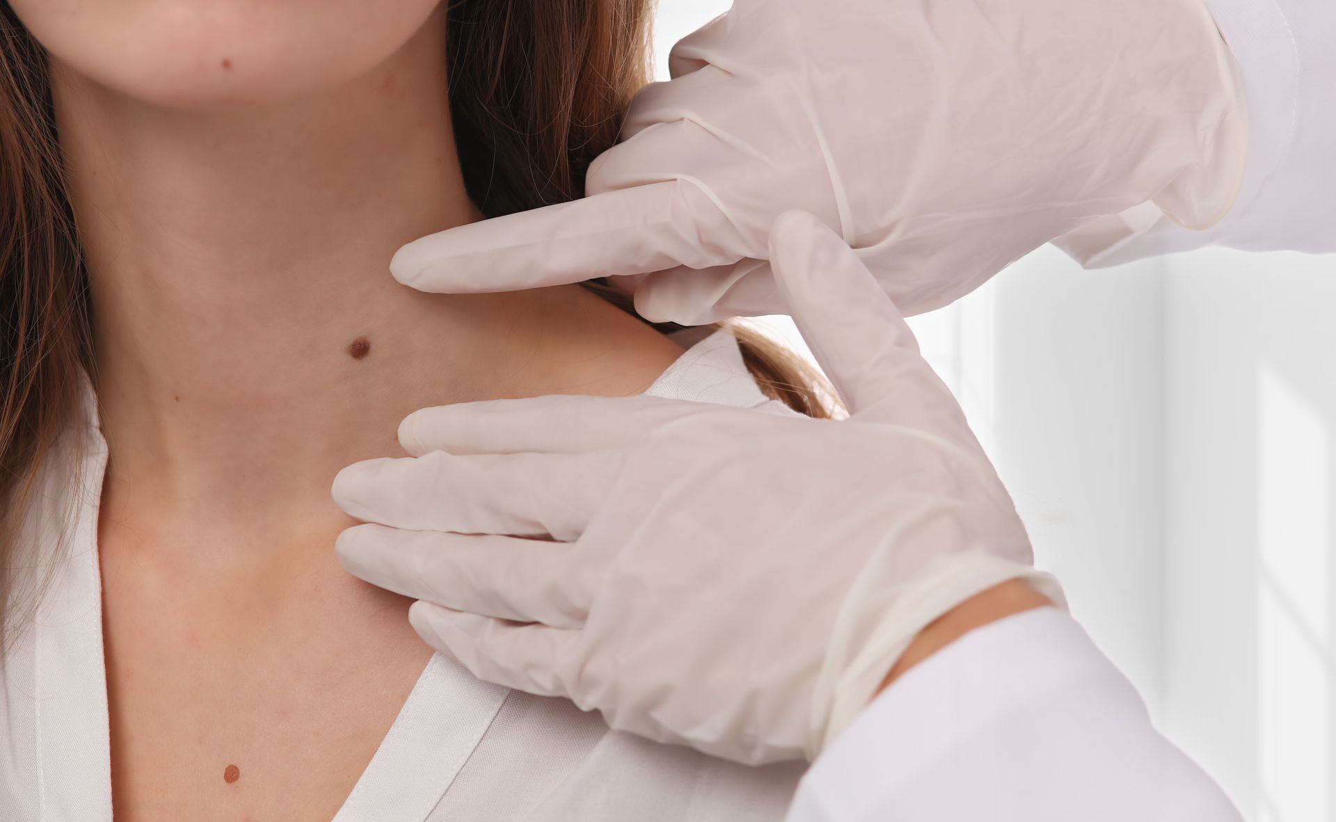 a doctor is examining a woman 's neck for a mole .