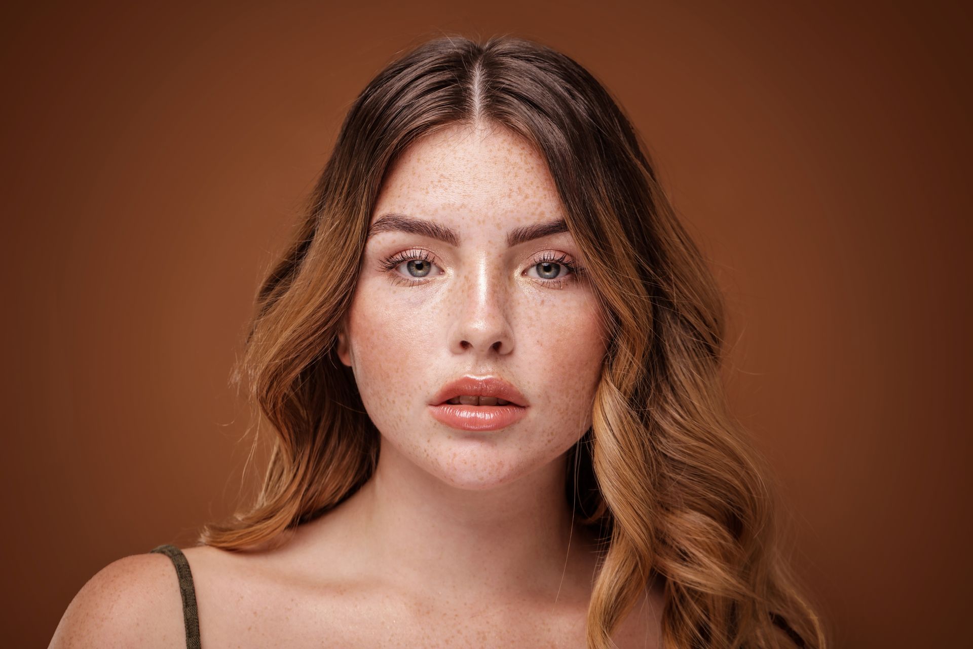 a woman with long hair and freckles is looking at the camera .