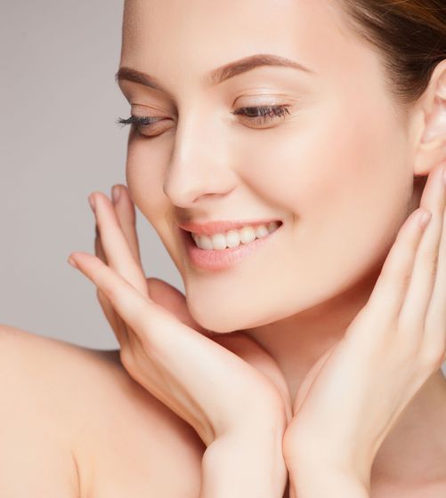 a woman is smiling and touching her face with her hands