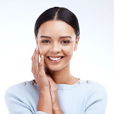 a woman in a blue sweater is smiling and touching her face .