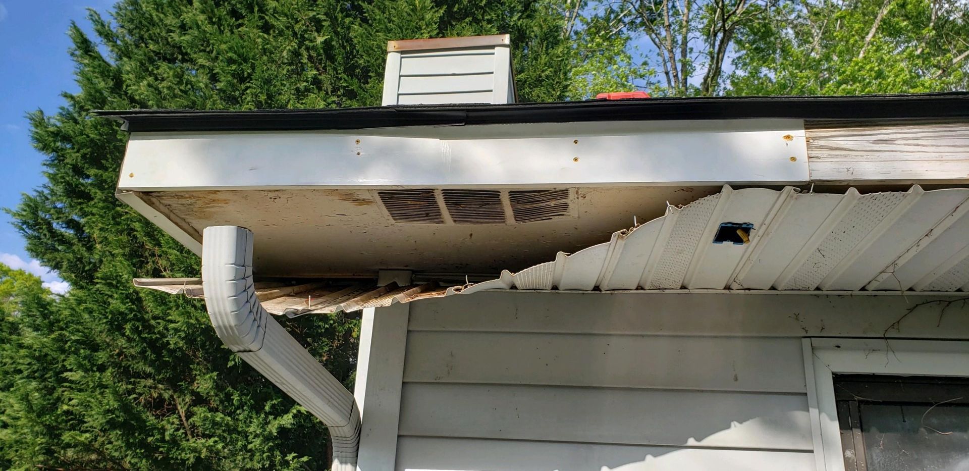a white house with a roof that has been damaged by a storm