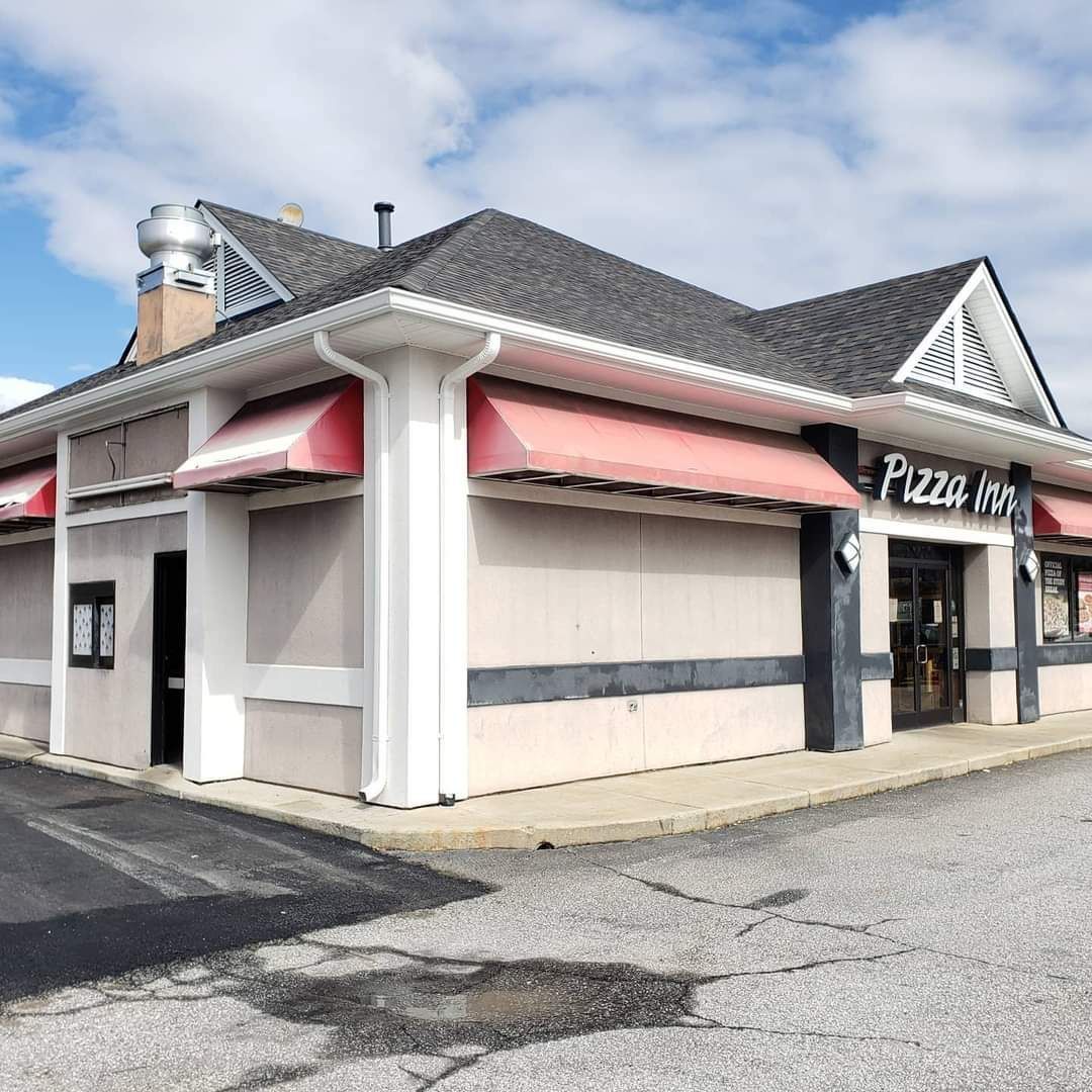 a pizza hut restaurant with red awnings on the side of it