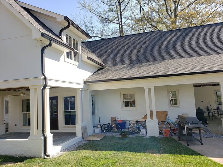 a white house with a black roof and a porch