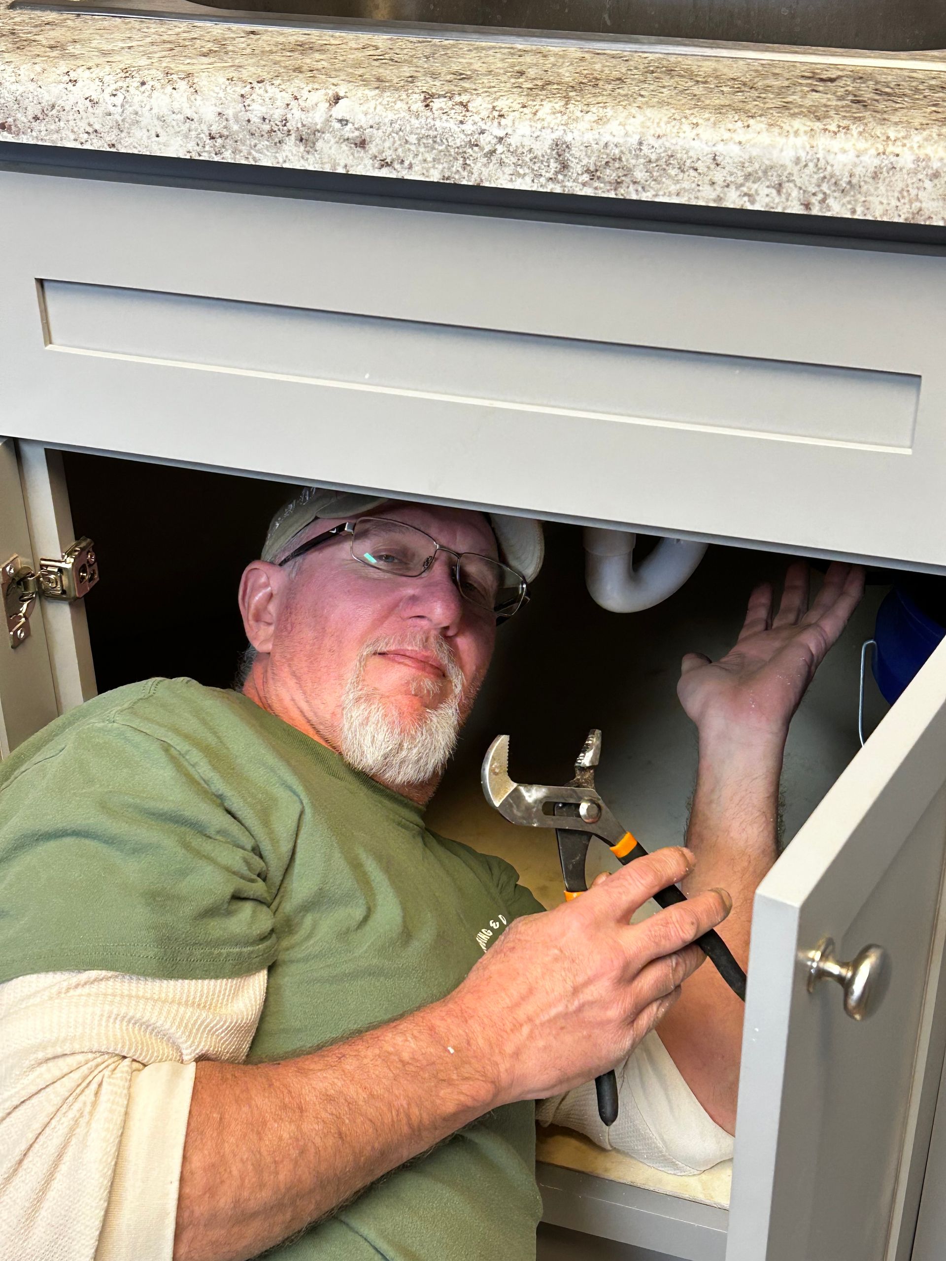 A plumber is fixing a sink in a bathroom with a wrench.