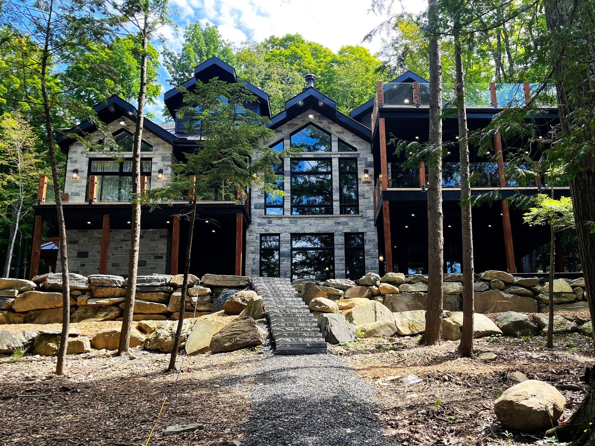 Une grande maison est entourée d'arbres et de rochers au milieu d'une forêt.