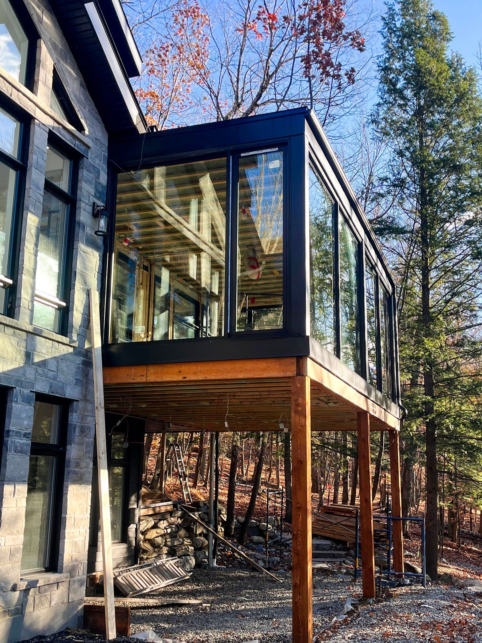 Une grande maison avec une grande terrasse et beaucoup de fenêtres entourée d'arbres.
