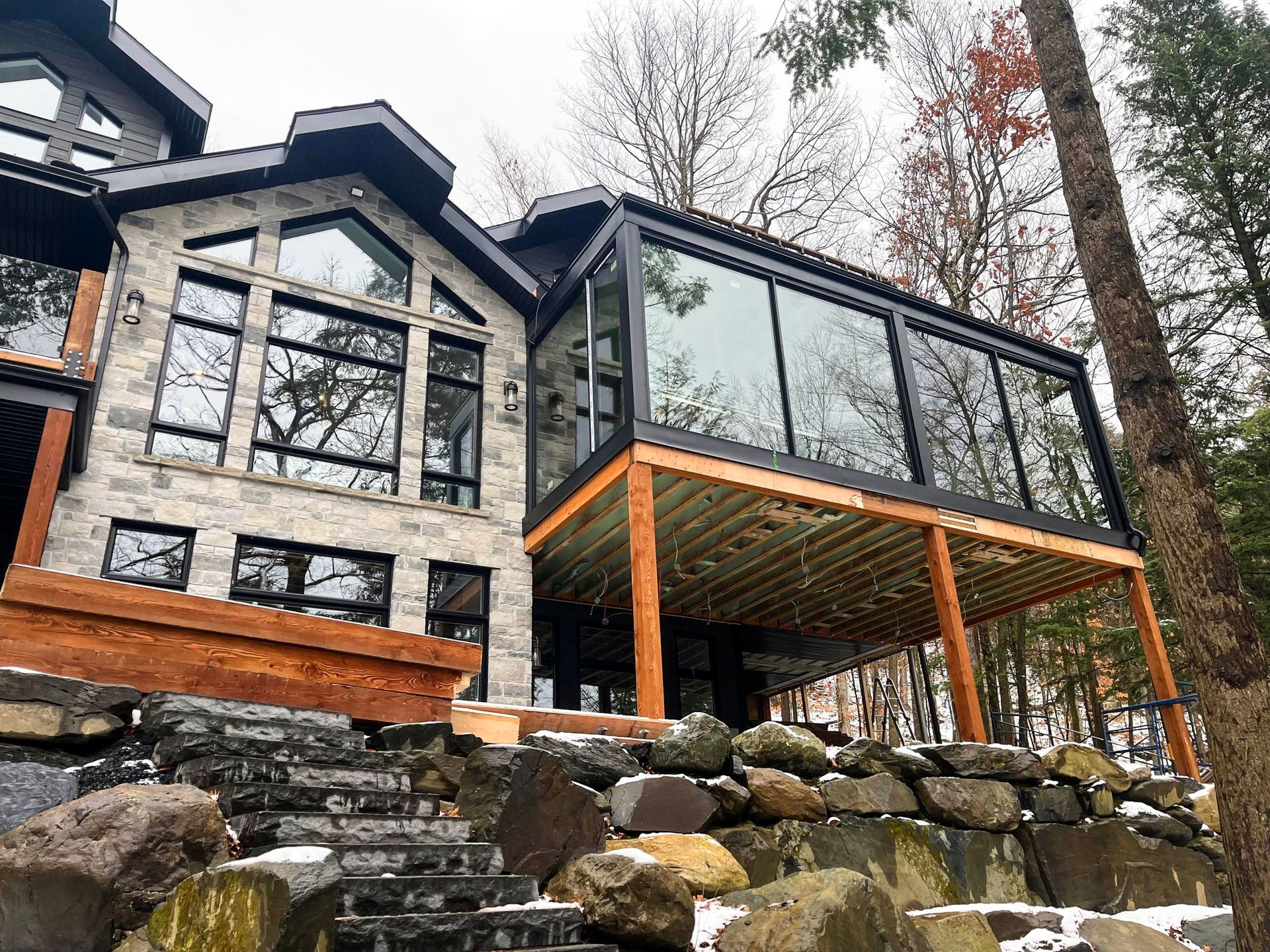 Une grande maison avec une grande terrasse entourée d'arbres et de rochers.