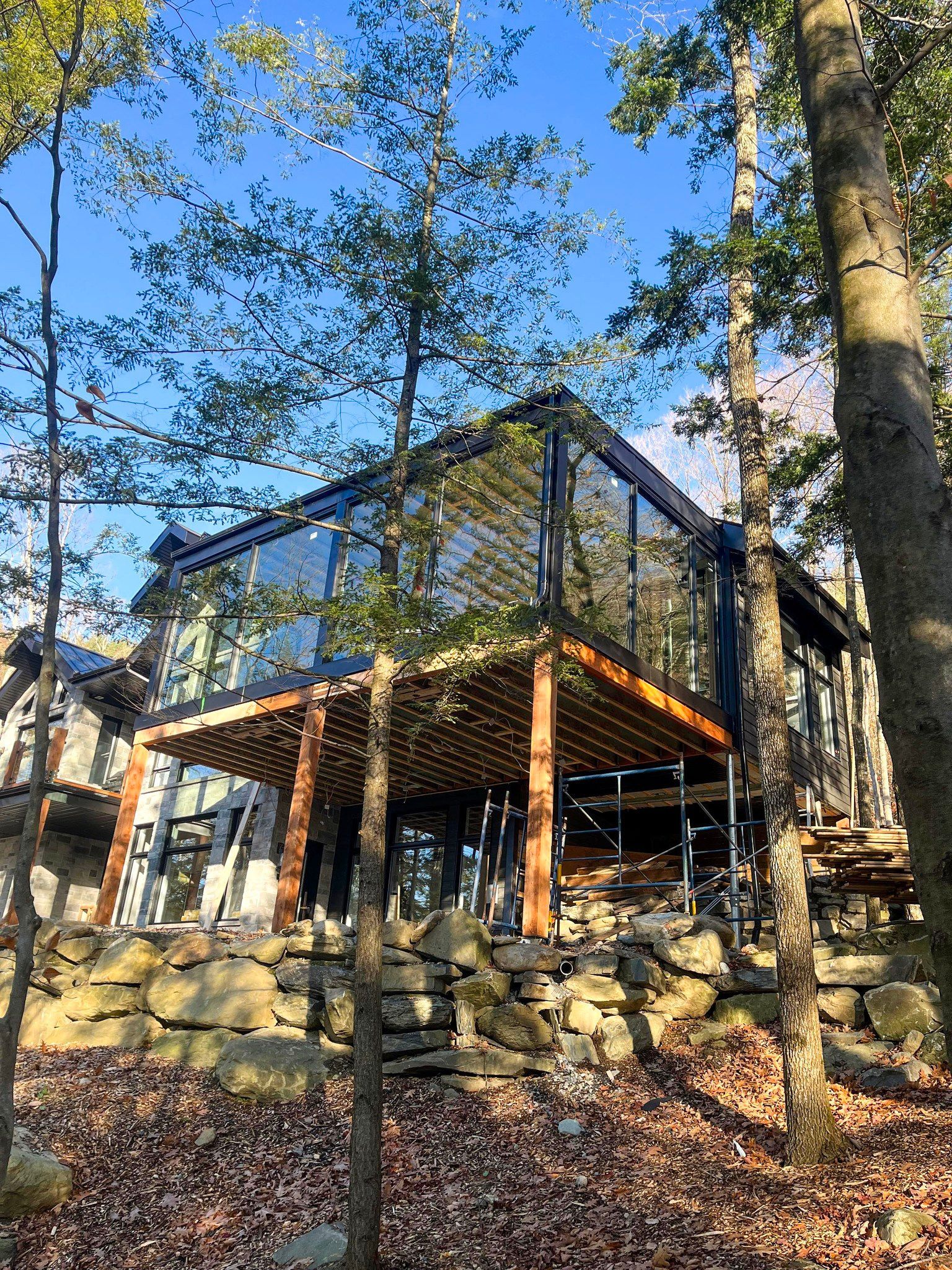 Une maison avec beaucoup de fenêtres est entourée d'arbres dans les bois.