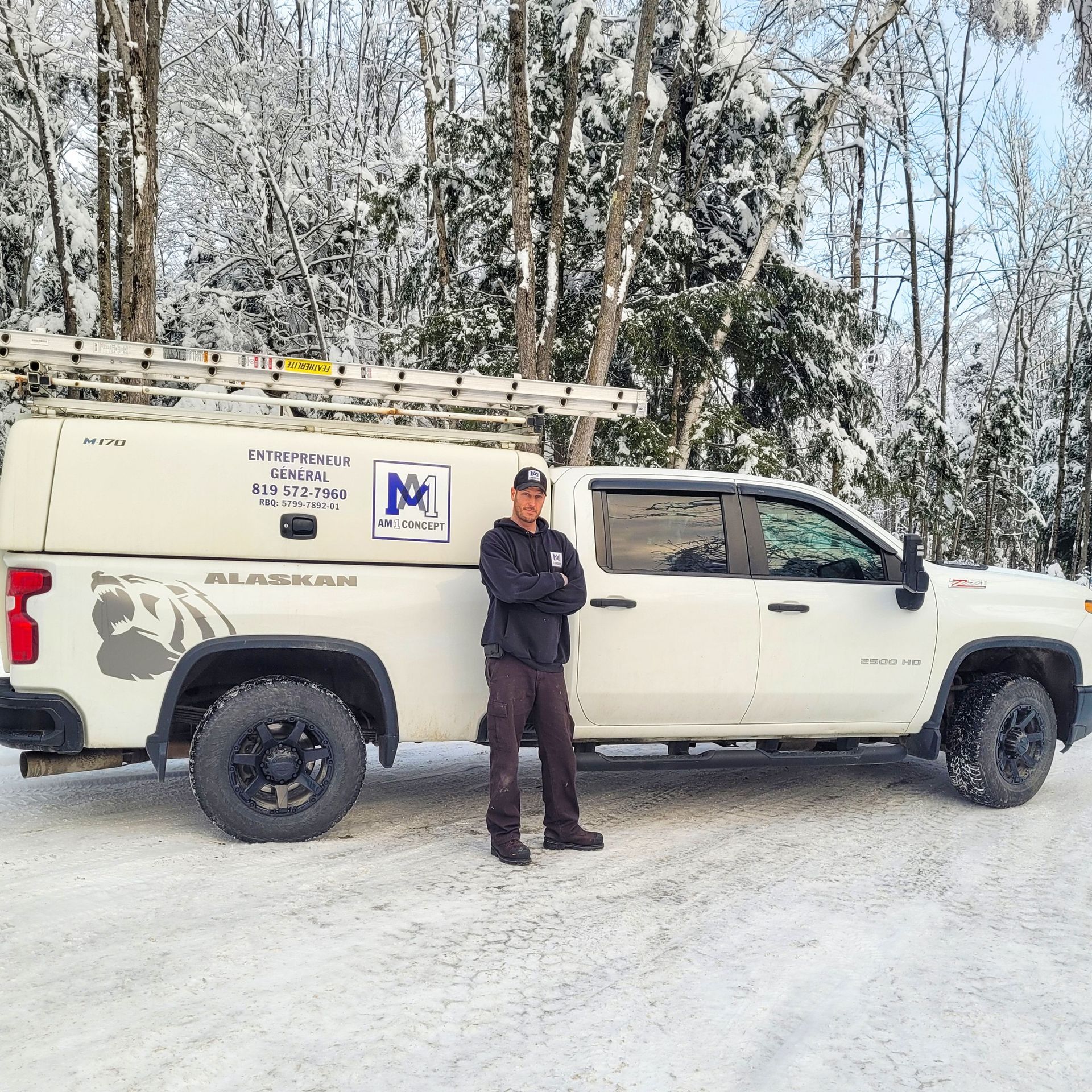 Un homme se tient devant un camion blanc avec la lettre m sur le côté