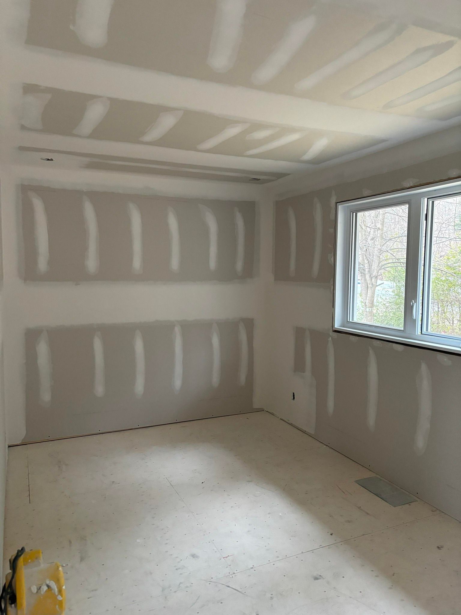 Une pièce avec beaucoup de cloisons sèches et une fenêtre.