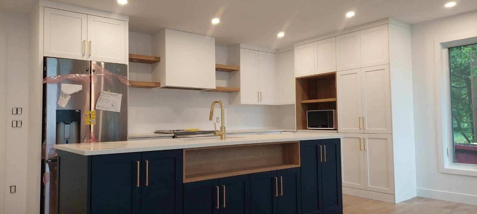 Une cuisine avec des armoires bleues, des armoires blanches, un réfrigérateur et un évier.