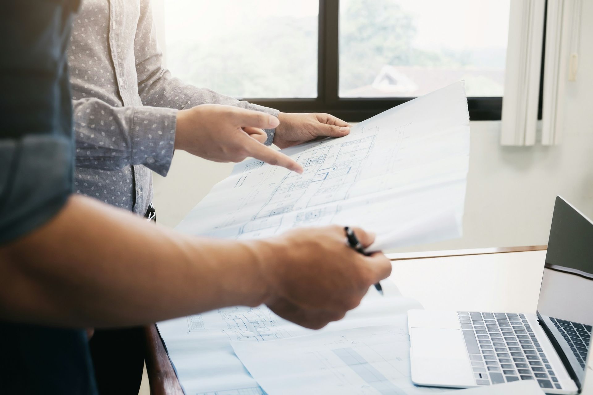 Un homme et une femme regardent un plan devant un ordinateur portable.