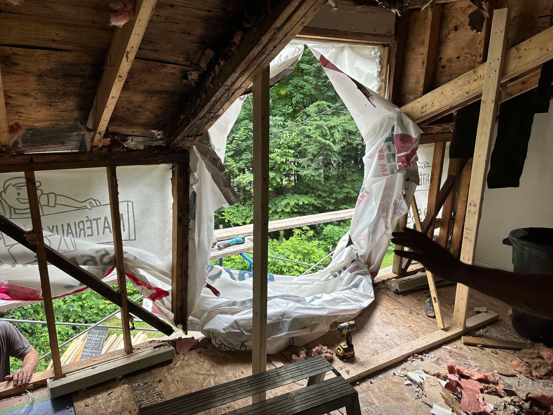 Une personne se tient dans une pièce avec une bâche couvrant la fenêtre.