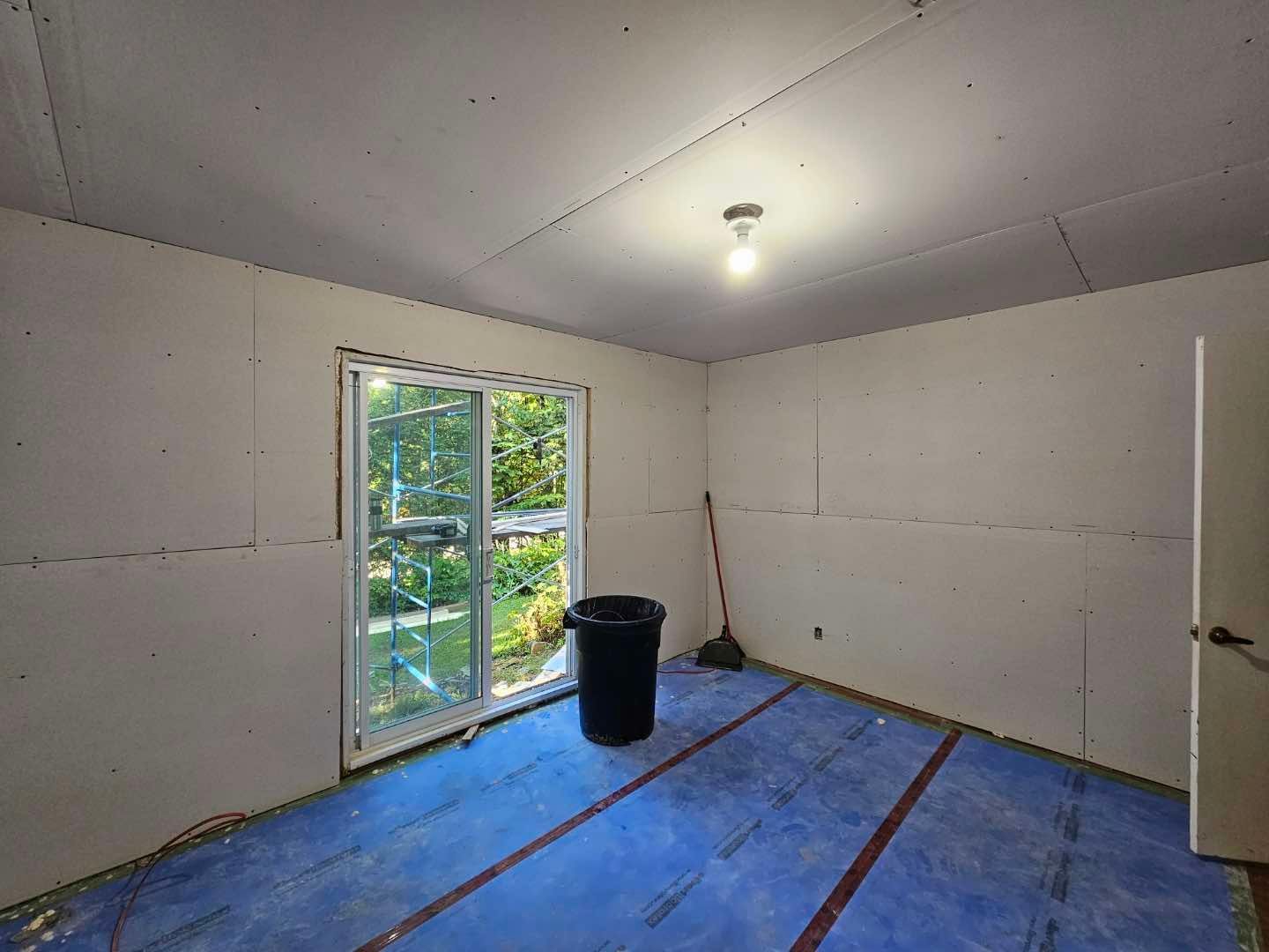 Une pièce avec une porte coulissante en verre et une poubelle à l'intérieur.