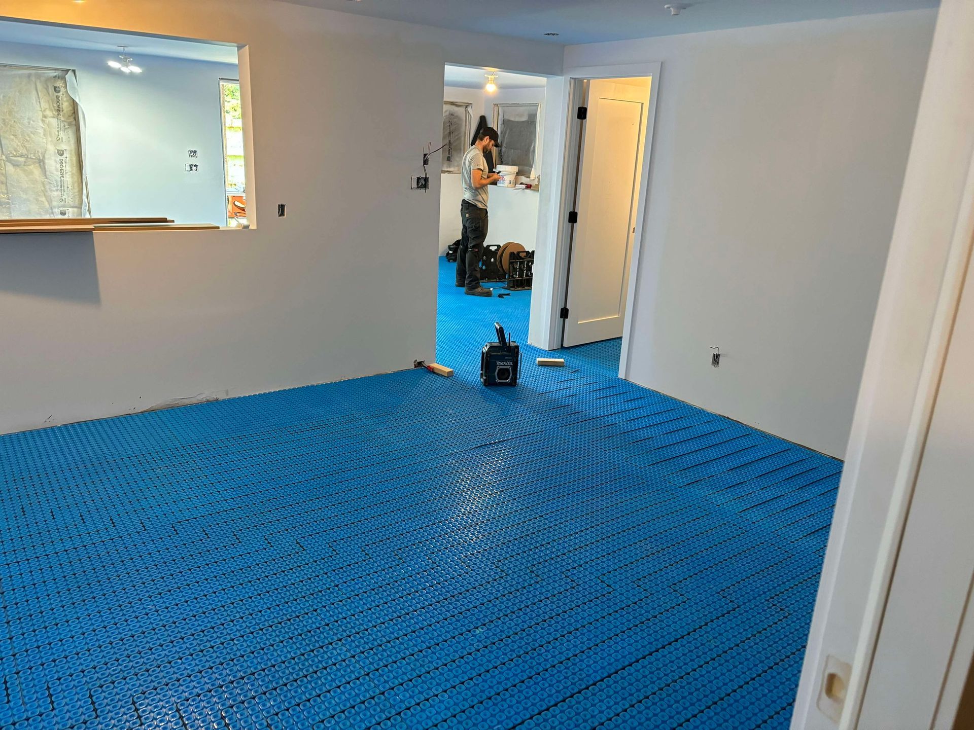 Un homme se tient debout dans une pièce avec un tapis bleu sur le sol.