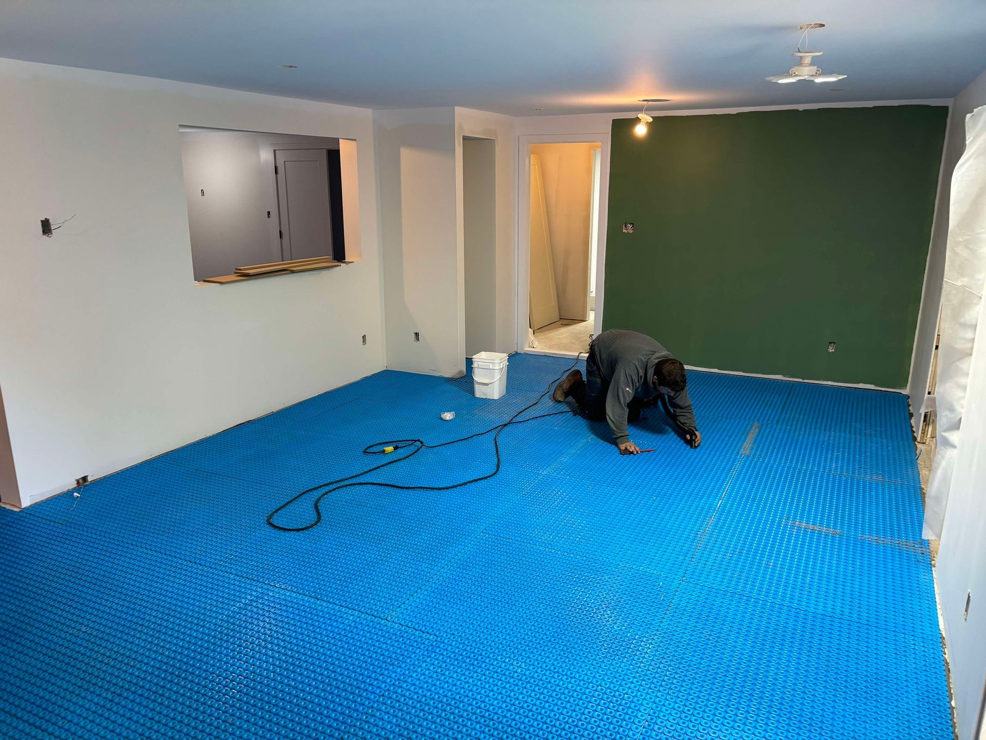 Un homme est agenouillé sur un tapis bleu dans une pièce.