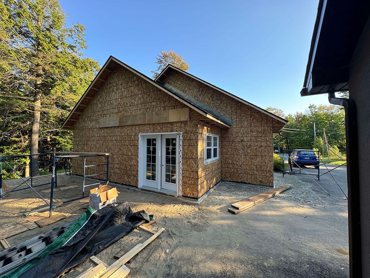 Une petite maison est en construction au milieu d'un champ de terre.