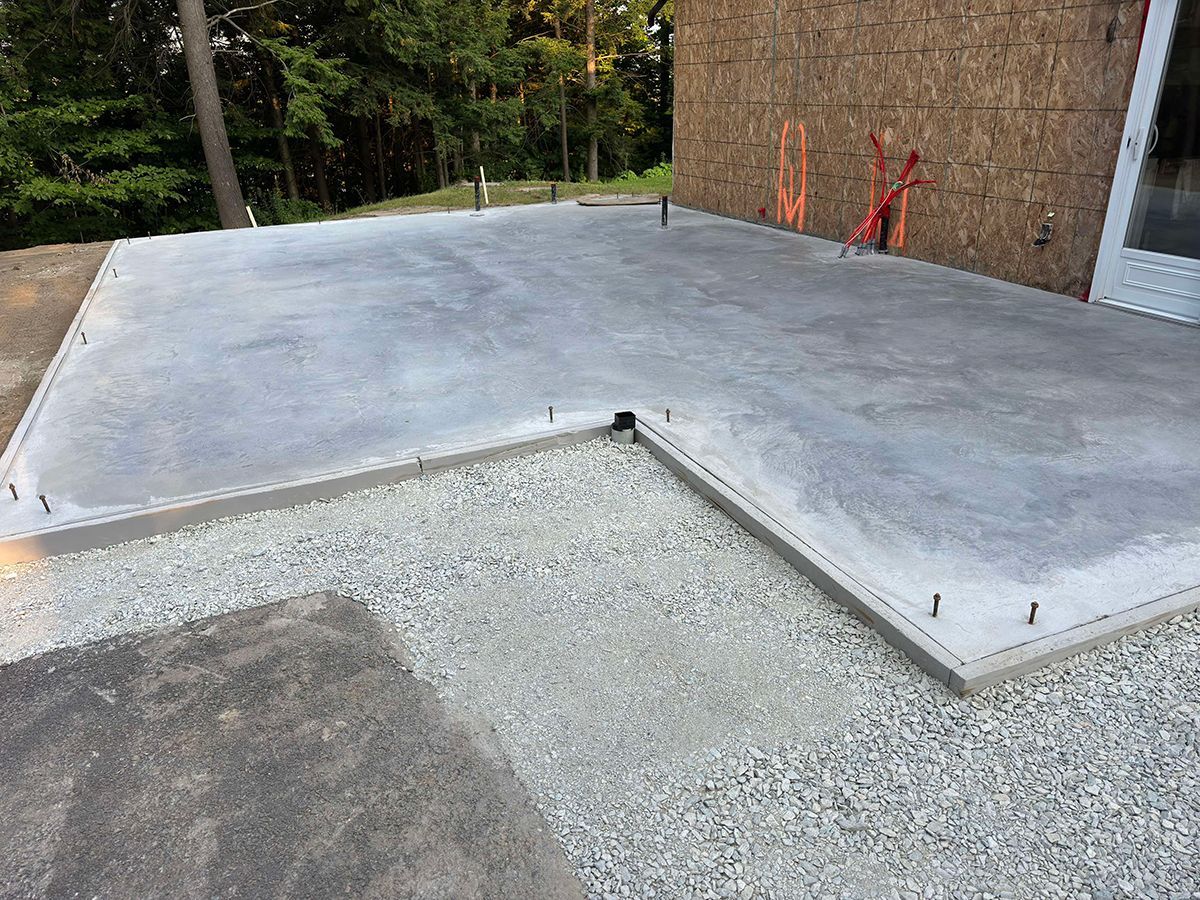 Un sol en béton est en train d'être construit devant une maison.