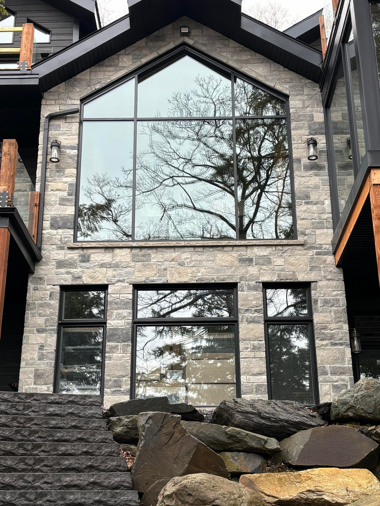 Une grande maison avec beaucoup de fenêtres et des arbres se reflétant dans les fenêtres.