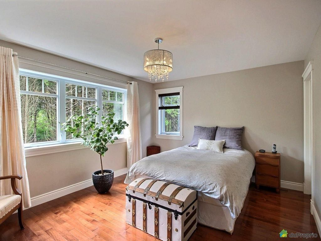 Une chambre avec un lit, un coffre, une chaise et une fenêtre.