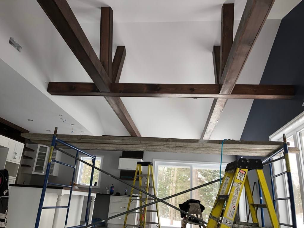 Un plafond avec des poutres en bois et une échelle dans une pièce.