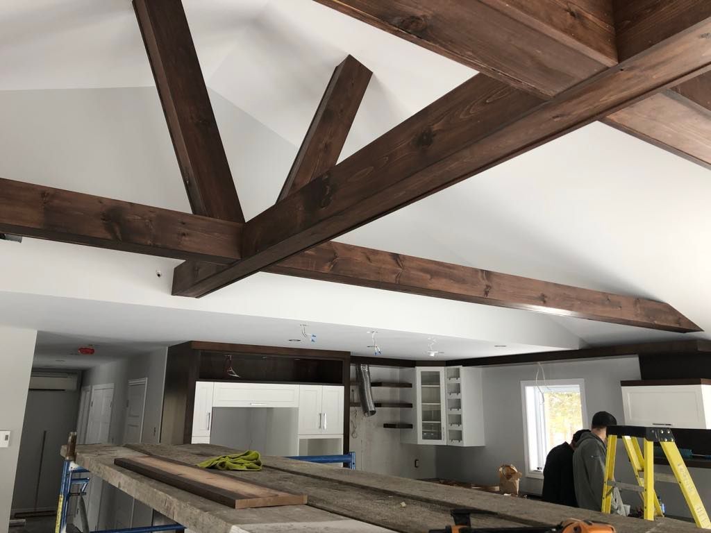 Un homme est debout sur une échelle dans une pièce avec des poutres en bois.
