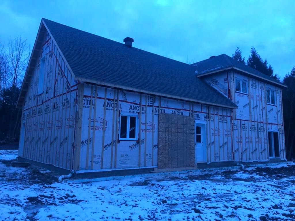 Une maison est en construction dans la neige avec un ciel bleu en arrière-plan.